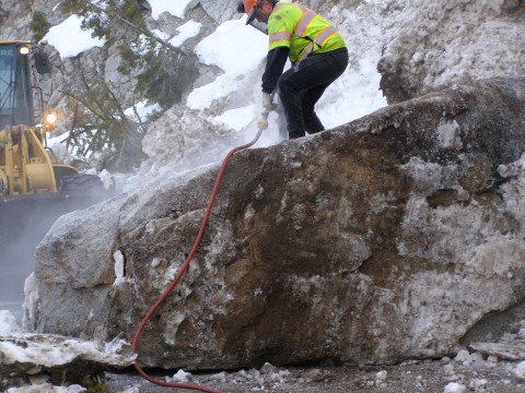 Operator Dakota Morgan of Stanley drills holes into a boulder to break it apart.
