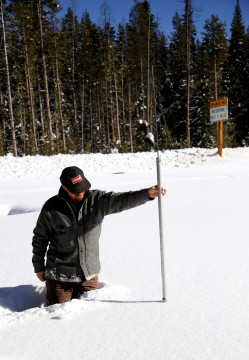 Brent Jenkins measures the snowpack depth at Banner Summit man holds pole in snow